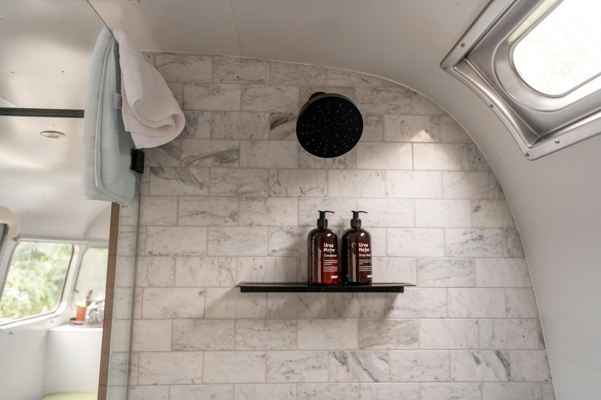 Modern bathroom interior in Airstream with marble tiles and luxury toiletries.